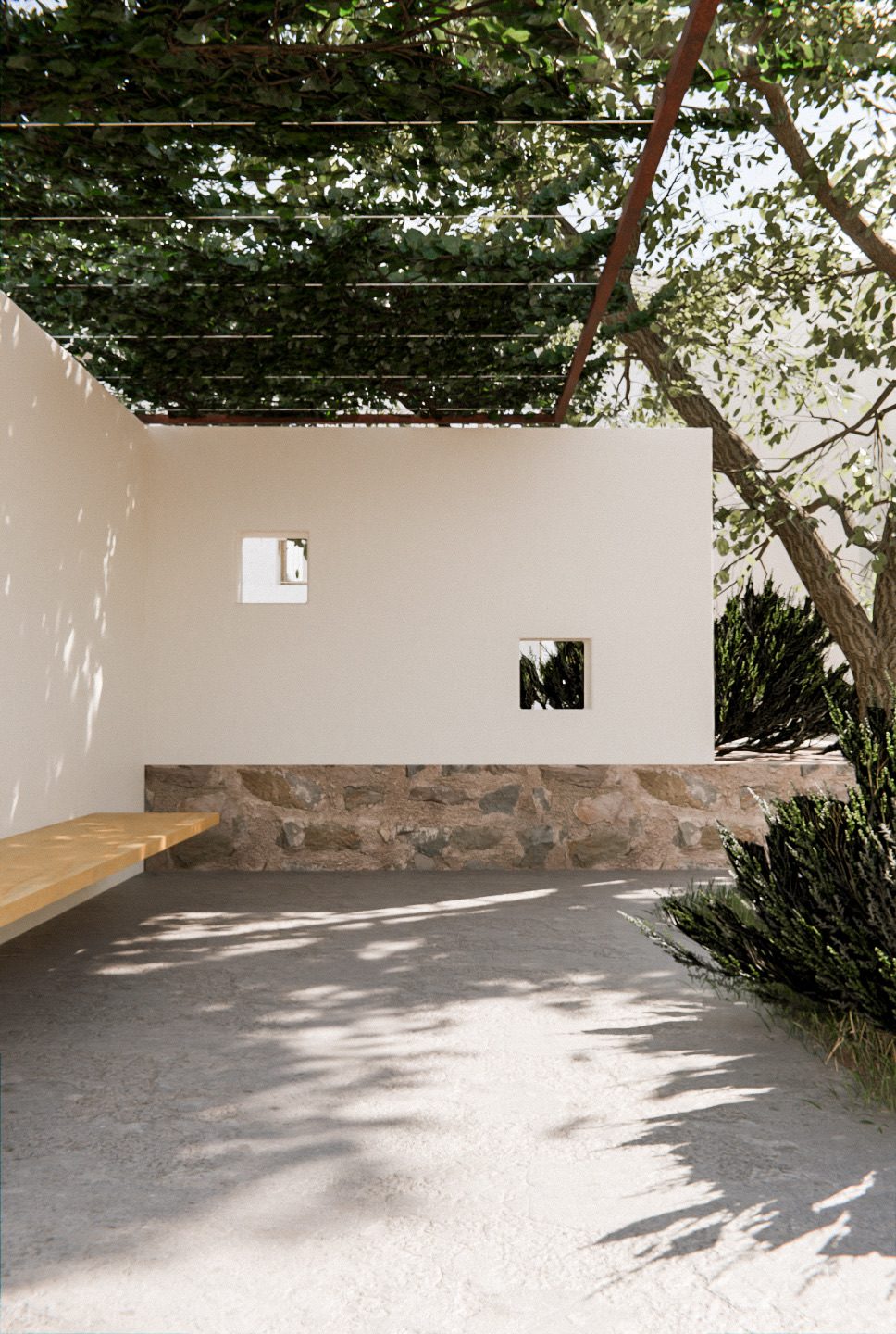 Patio de una vivienda proyectada por Andrés Vázquez: muro encalado sobre zócalo de piedra bajo una pérgola con parra